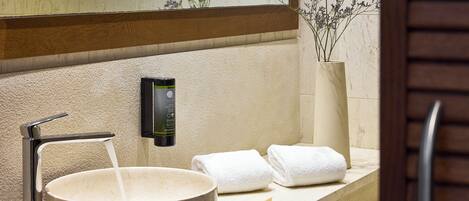 A bathroom with a large basin, a towel rack, and a soap dispenser.