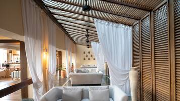 A modern hotel lobby with a white sofa, a large potted plant, and a wooden ceiling.