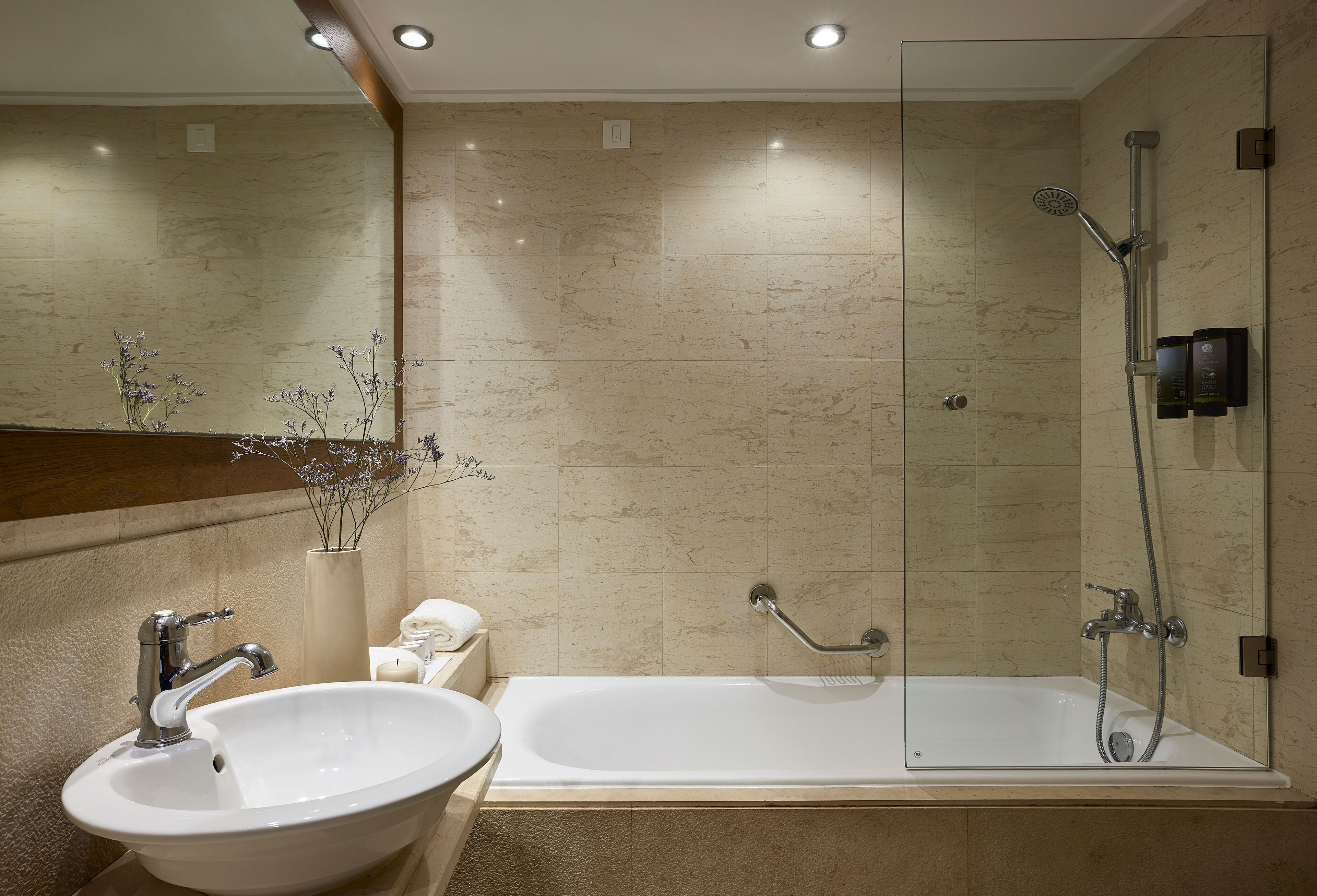 A modern bathroom with a sink, mirror, and a glass-enclosed shower area.
