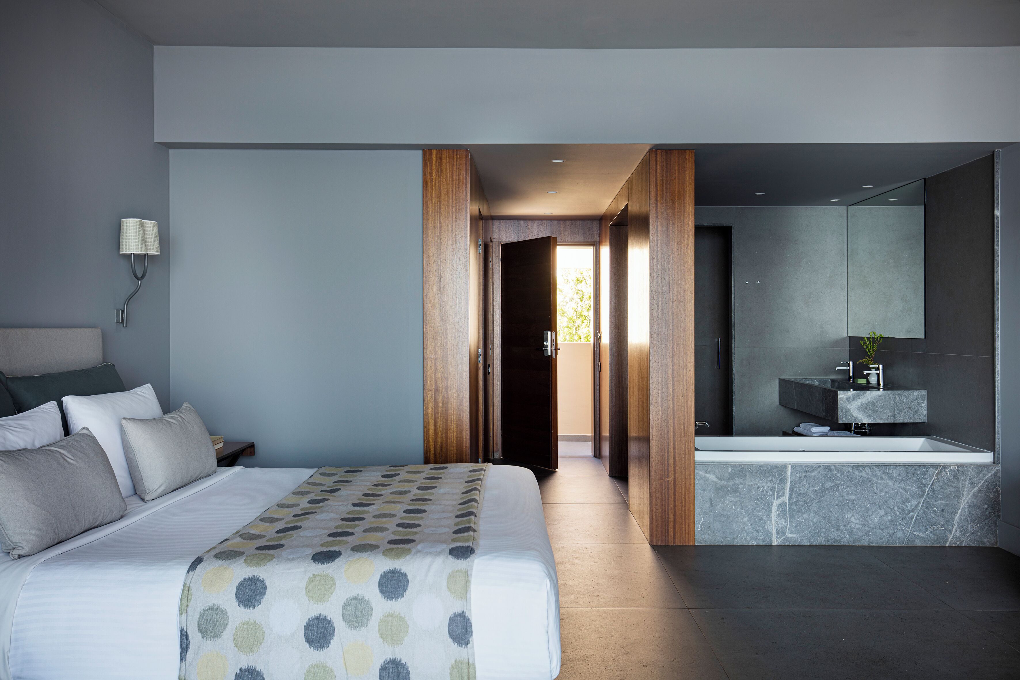 Una habitación de hotel moderna con una cama grande, un baño con bañera y vistas al exterior.