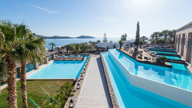 Un complexe hôtelier doté de plusieurs piscines, offrant une vue dégagée sur la mer et comprenant un jardin bien entretenu.