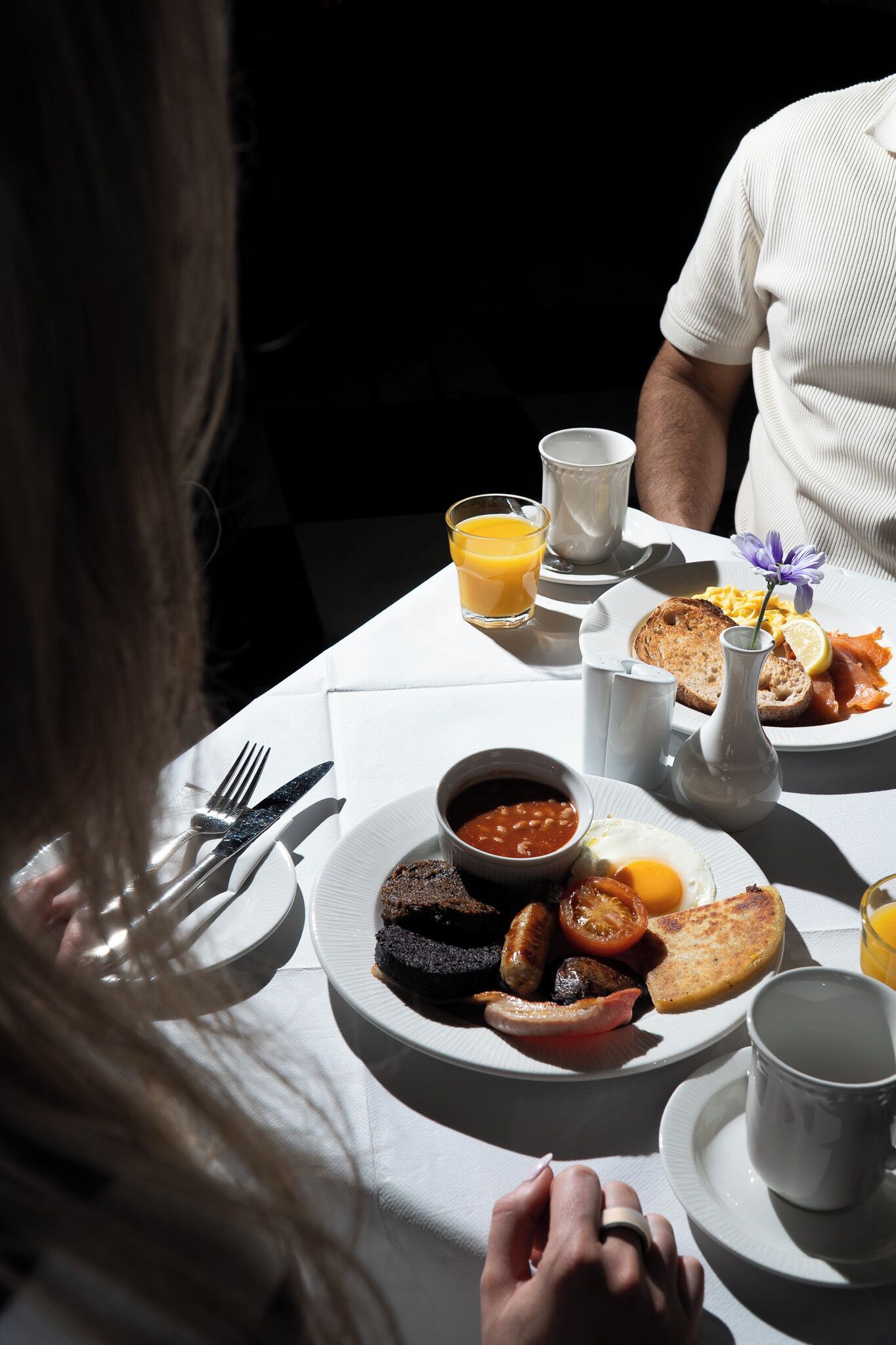 A breakfast setting with a plate of eggs, bacon, and toast, a glass of orange juice, and a cup of coffee.