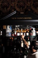 A bar area with a variety of liquor bottles and a sign reading 'NEW TOWN HOTEL'.