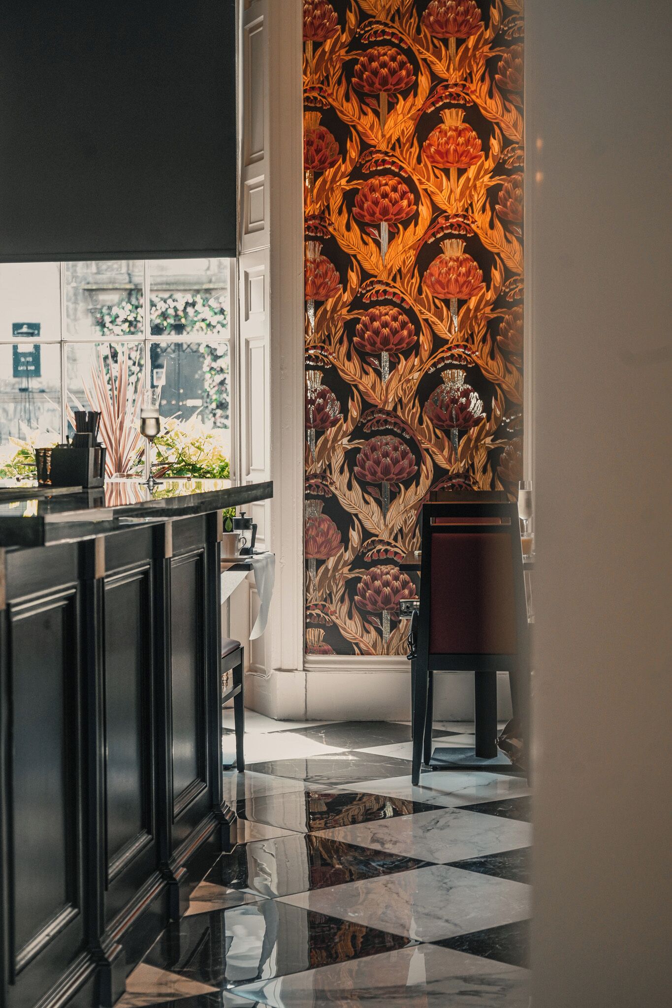 Eine moderne Küche mit einem schwarz-weiß karierten Boden, einem dunklen Holzschrank und einer Wand mit einem floralen Tapetenmuster.