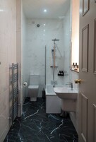 A modern bathroom with a shower, toilet, and sink.