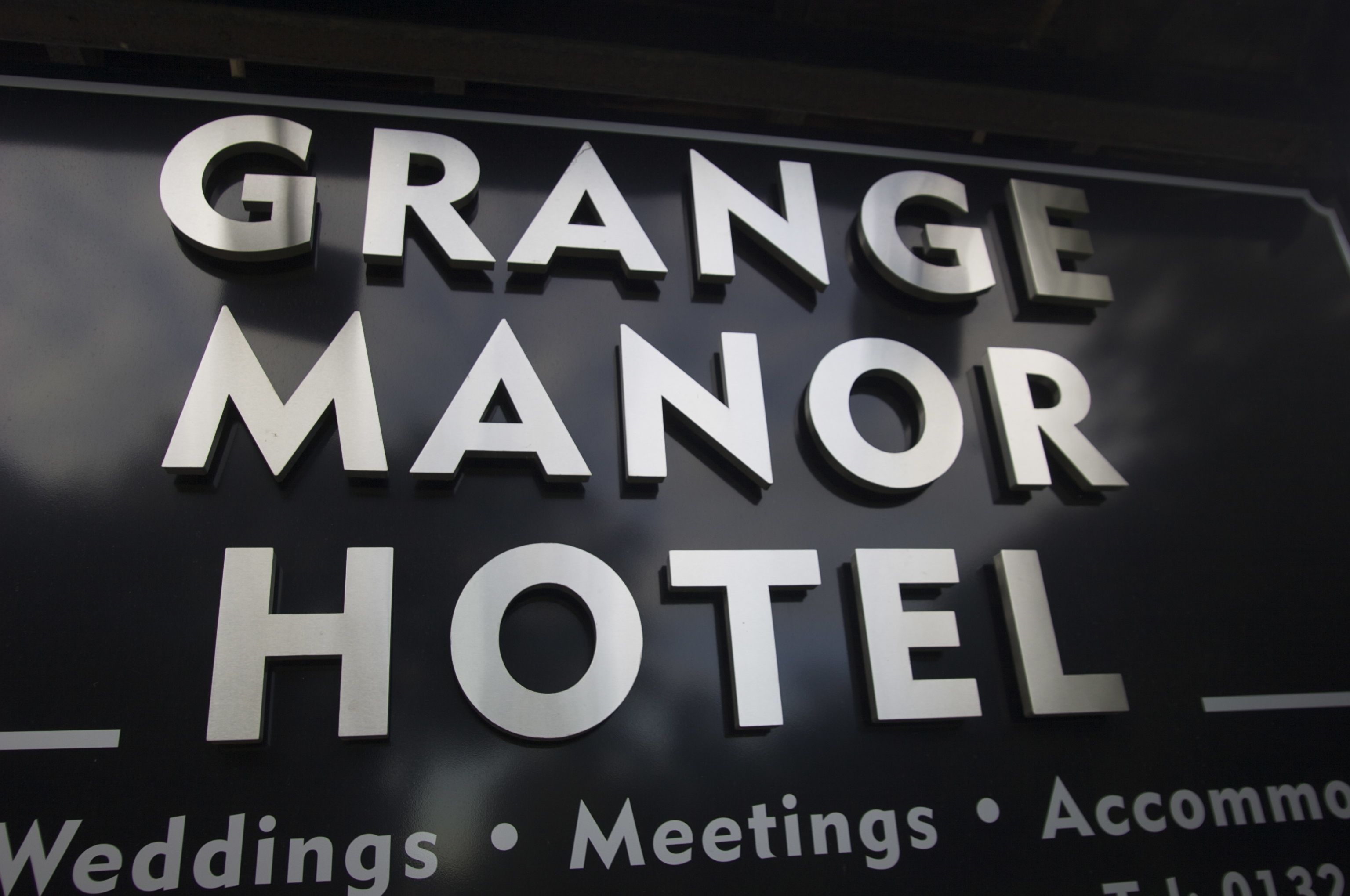 Letrero del Hotel Grange Manor con las palabras 'Bodas, Reuniones, Alojamiento' visibles.