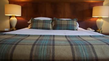 Una cama bien hecha con ropa de cama escocesa y dos lámparas de noche.