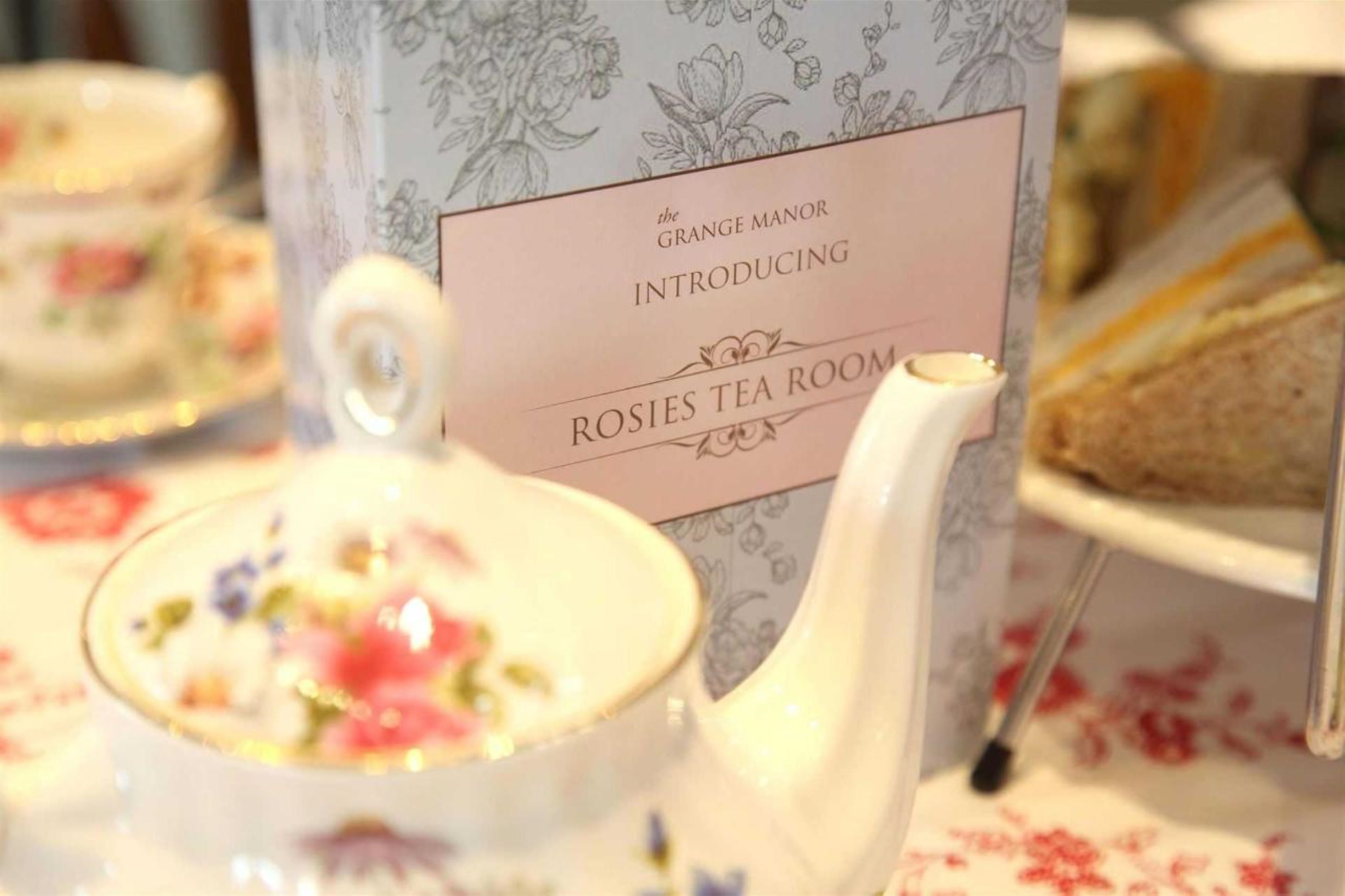 Uma sala de chá com toalhas de mesa estampadas com flores e um letreiro de apresentação.