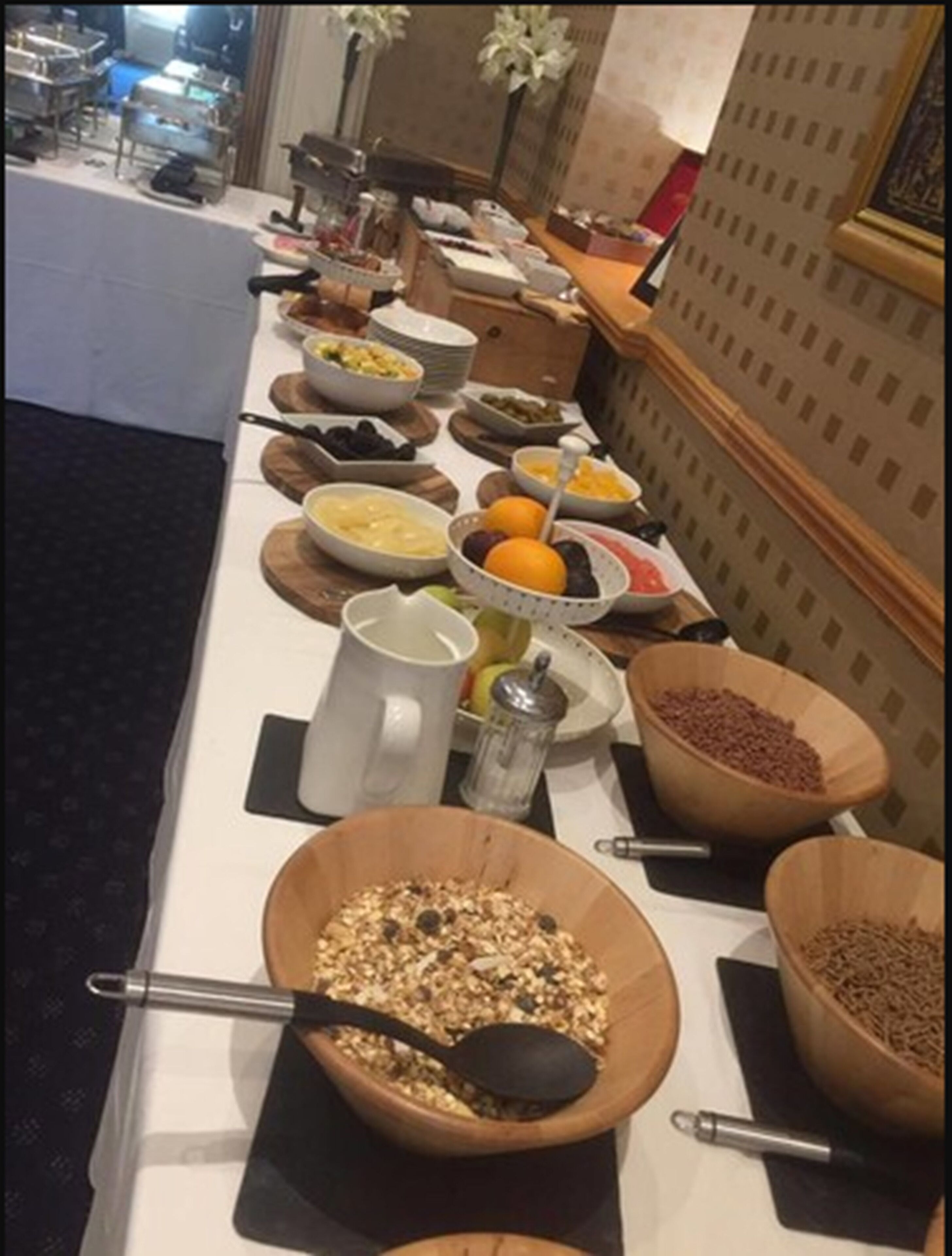 A buffet table with various food items and utensils.