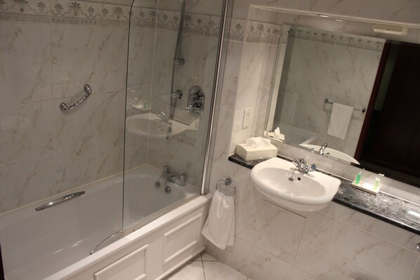 Un baño moderno con ducha envuelta en vidrio, un lavamanos blanco y un espejo grande.