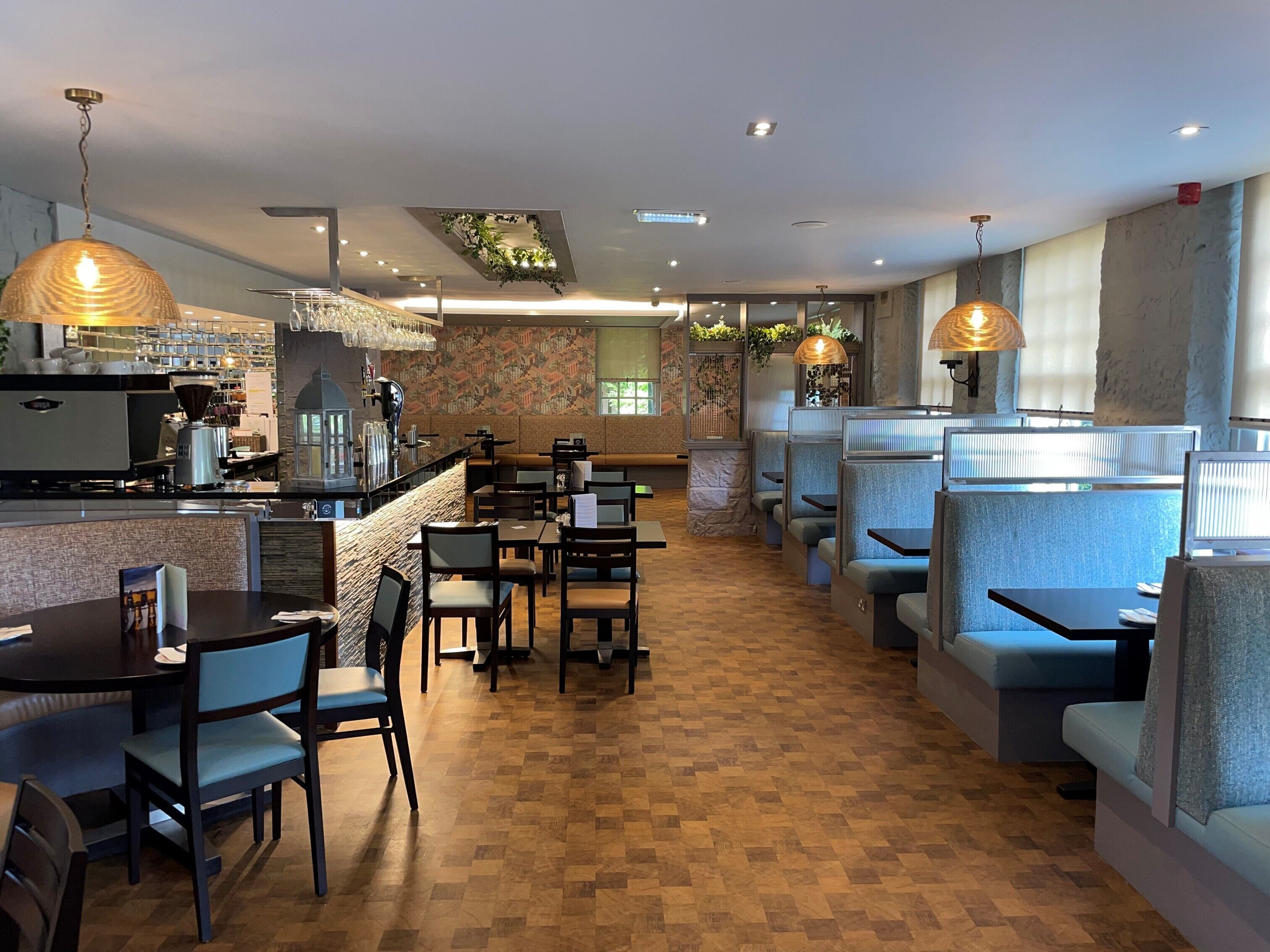 A restaurant with booths and tables, a bar area, and a patterned wall.