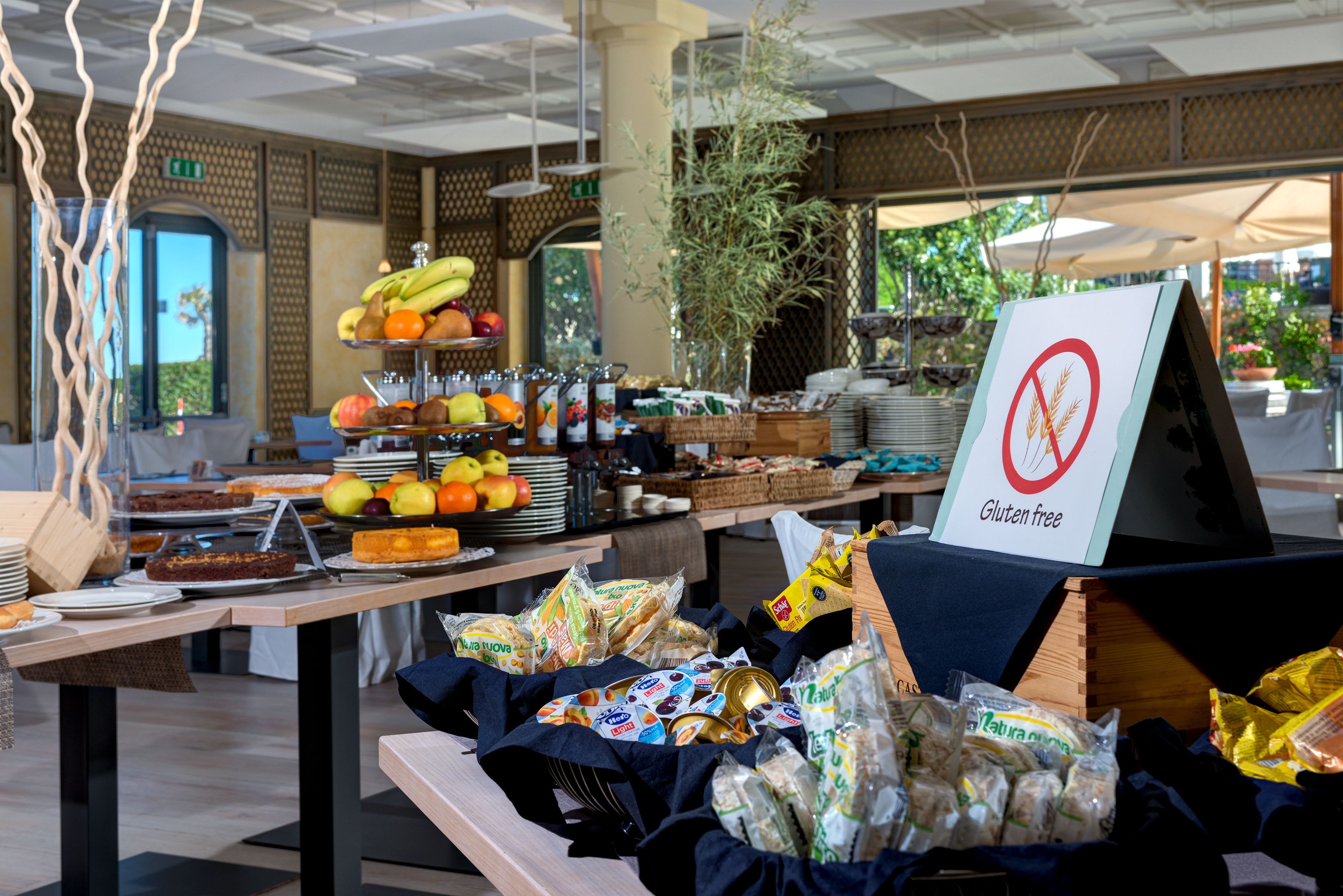 Una mesa de buffet con diferentes alimentos y un cartel que indica opciones sin gluten.