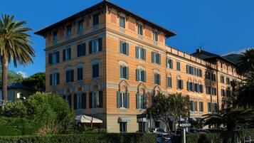 A multi-story building with a classic architectural style, featuring a symmetrical facade, multiple windows with shutters, and a flat roof.