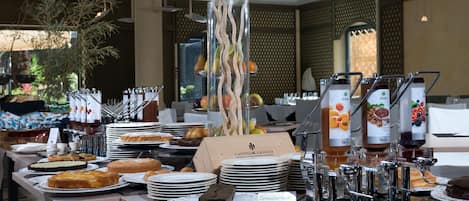 Un bufé con diferentes opciones de comida, incluyendo pasteles, bollos y bebidas.