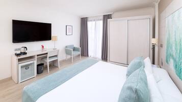 Una habitación de hotel con cama, escritorio con silla, televisor, máquina de café y armario.