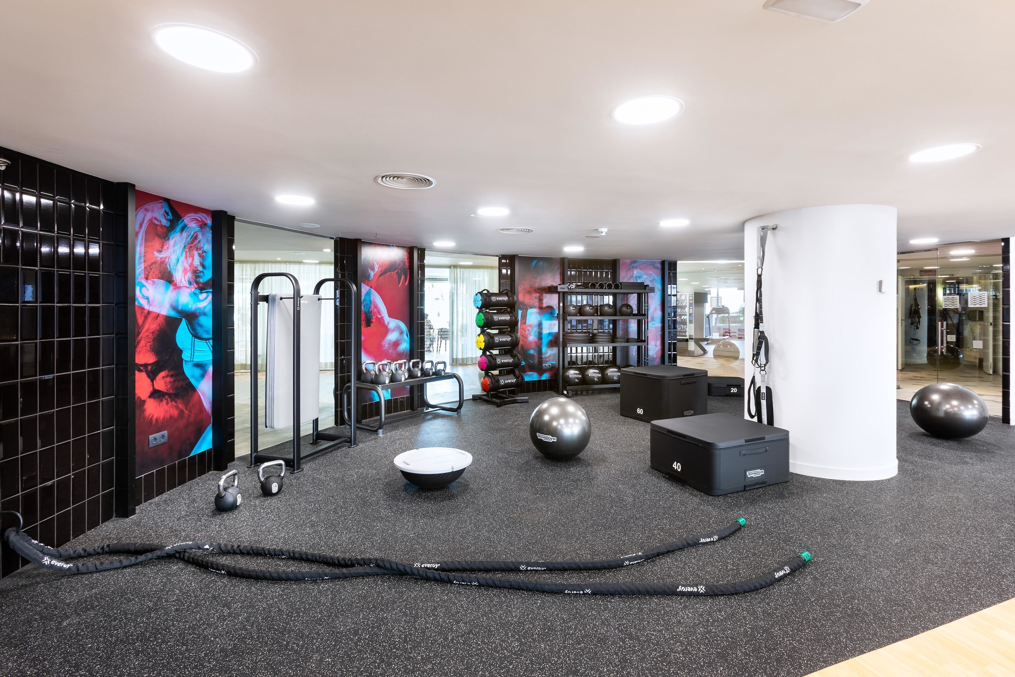 Un gimnasio moderno con equipo de ejercicio, un espejo grande y decoración de pared motivacional.