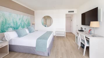 A hotel room with a bed, a desk, a chair, a TV, and a large mirror.