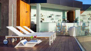 A modern outdoor bar area with lounge chairs, a bar counter, and a glass enclosure.