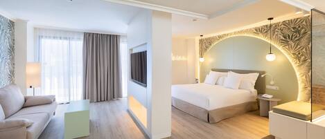 A hotel room with a bed, bedside table, lamp, and a sofa.