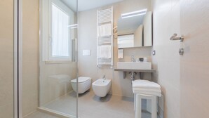 A modern bathroom with a glass shower enclosure, a bidet, a toilet, and a sink with a mirror above it. - Hotel Delfino (Mestre)