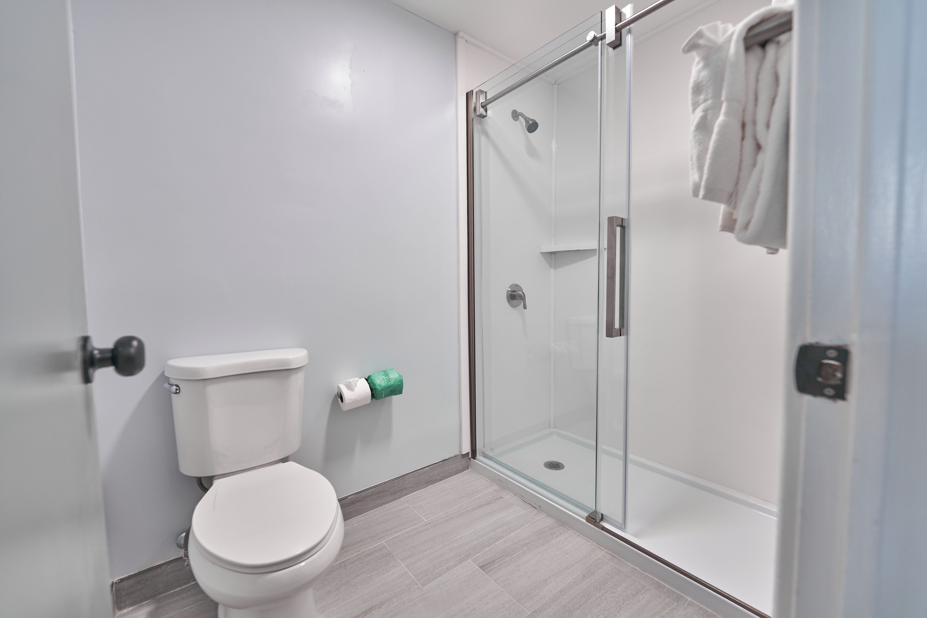 Un baño moderno con inodoro, cabina de ducha de vidrio y una toalla colgada en la pared.