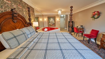 A hotel room with a large bed, a wooden headboard, a red chair, a desk, and a mirror.