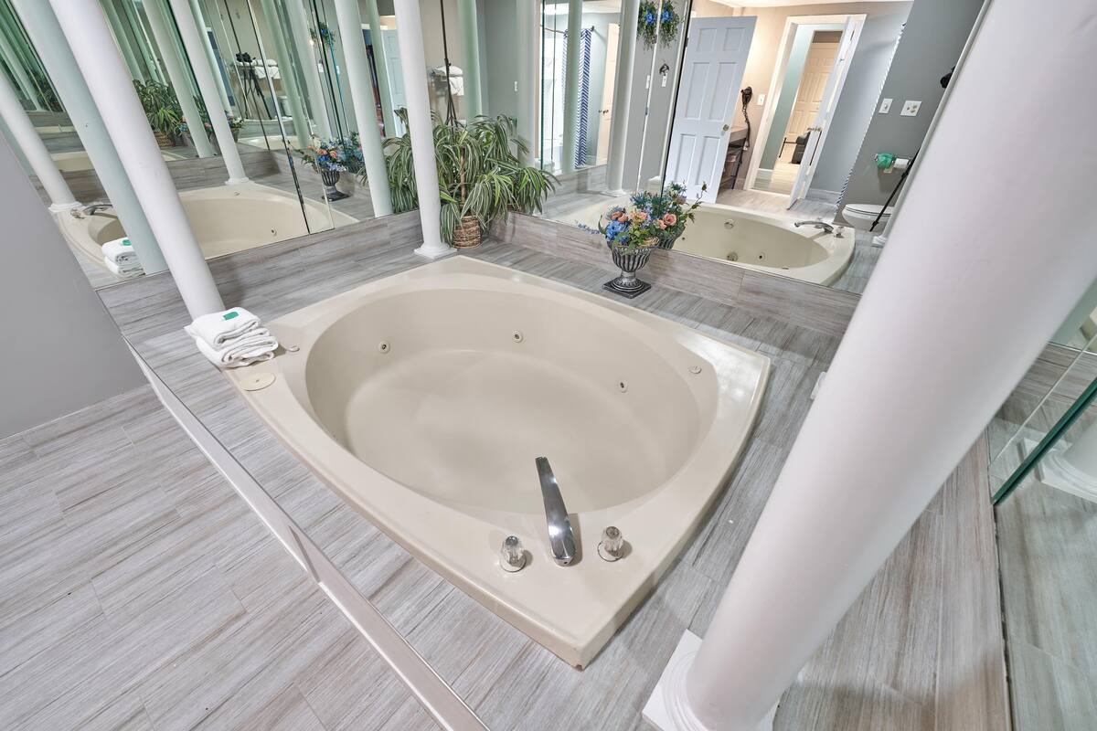 Une salle de bain moderne avec une grande baignoire, un miroir et une plante en pot.