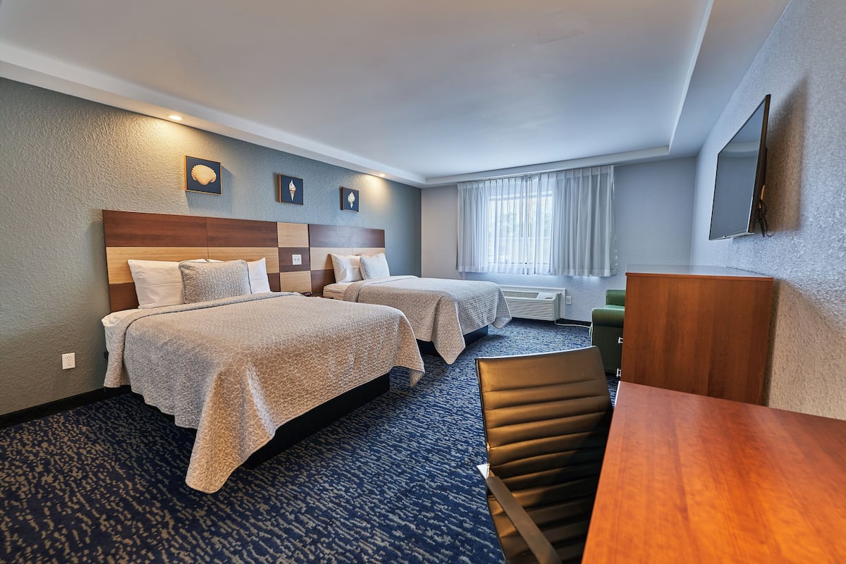 Une chambre d’hôtel avec deux lits, un bureau et une chaise.