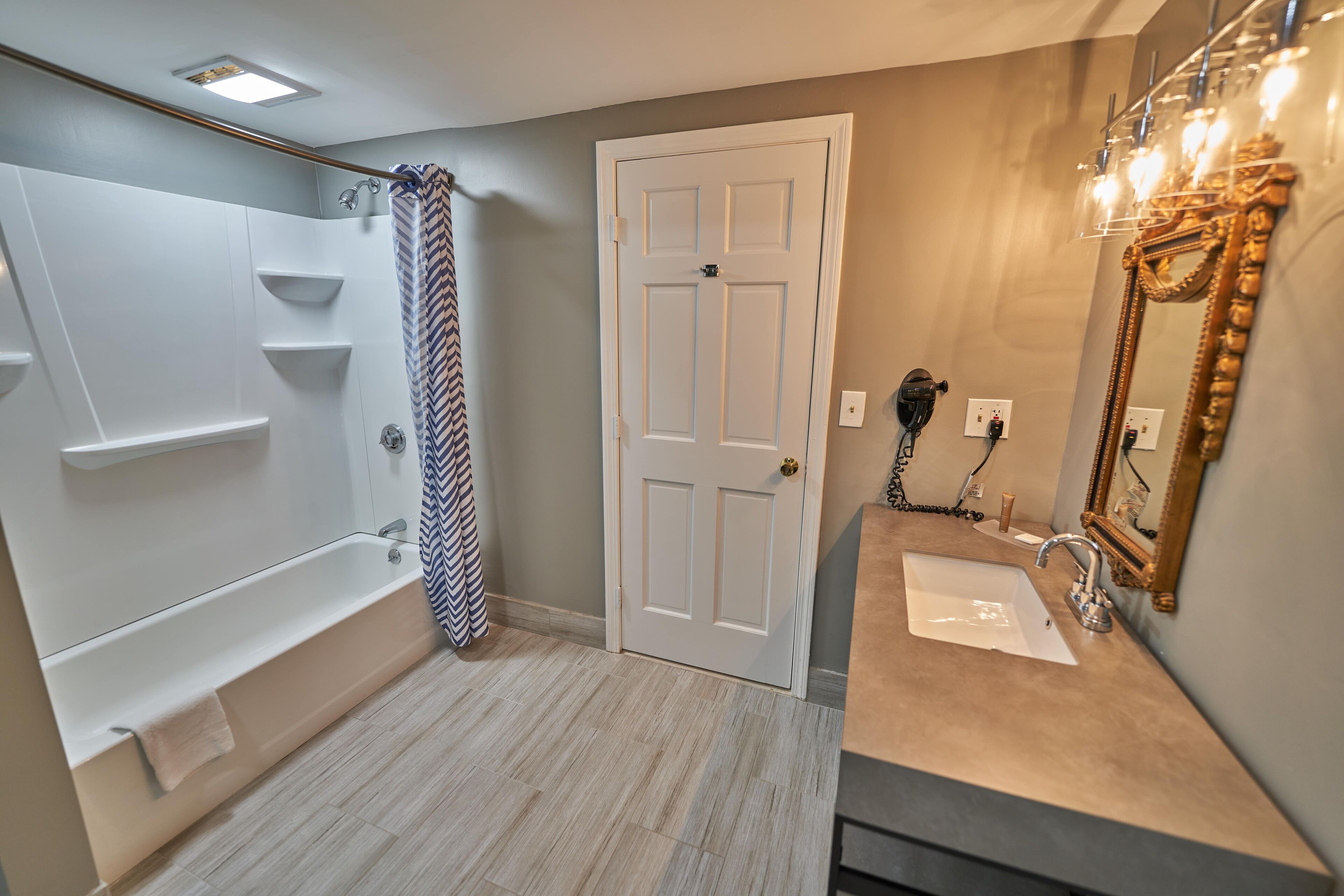 Une salle de bain équipée d’une baignoire, d’une douche, d’un meuble-lavabo et d’un grand miroir.