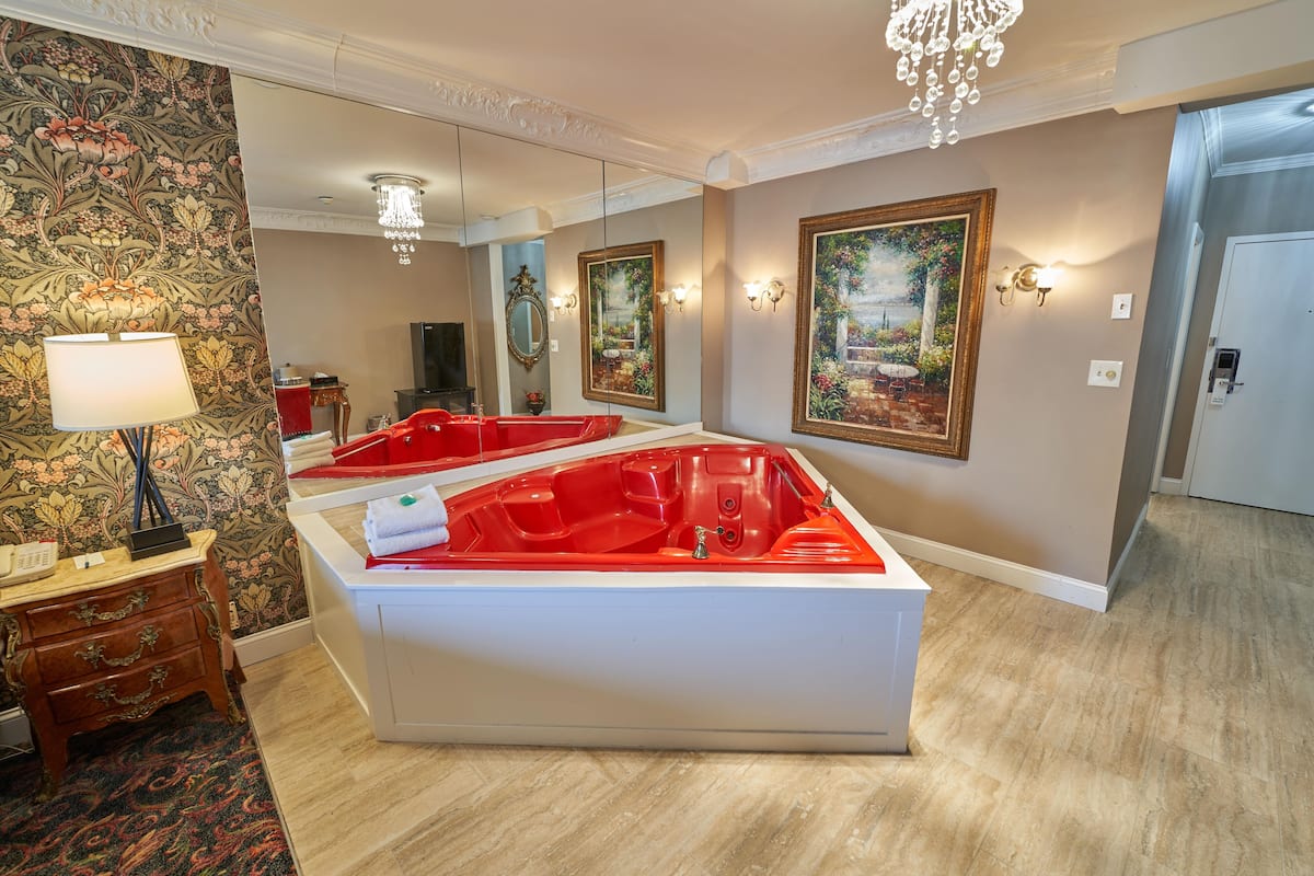 Une salle de spa dotée d’une grande baignoire, d’un miroir et d’un lustre.