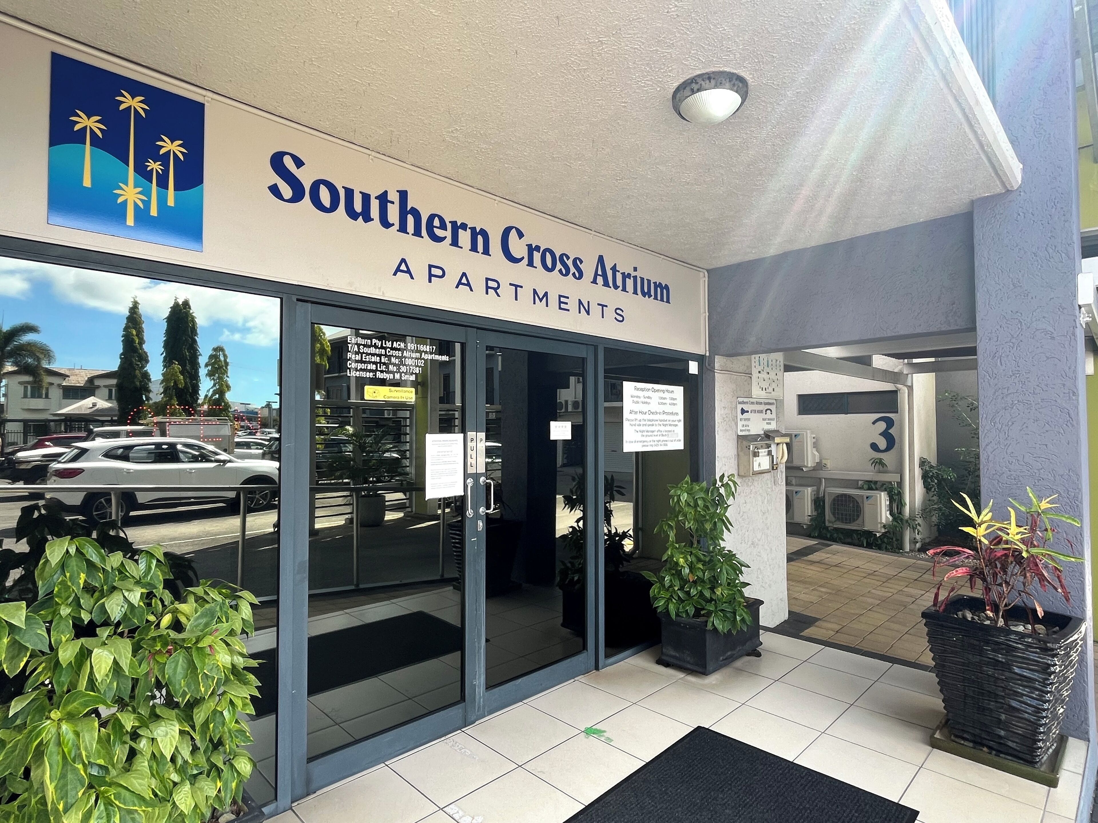The entrance to Southern Cross Atrium Apartments with a clear view of the parking area and surrounding buildings.