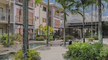Un bâtiment moderne doté de nombreux balcons, d’une piscine et d’une végétation luxuriante.