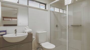 Un baño con lavabo, inodoro y cabina de ducha de vidrio.