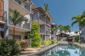 Ein Hotel mit Swimmingpool, Terrassenmöbeln und Palmen.