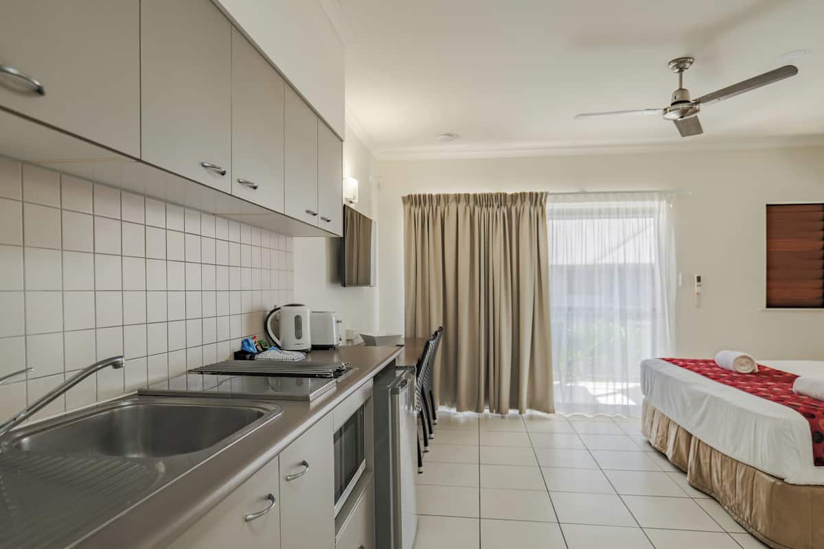 A modern kitchen with a built-in oven, a sink, and a dining area with a table and chairs.