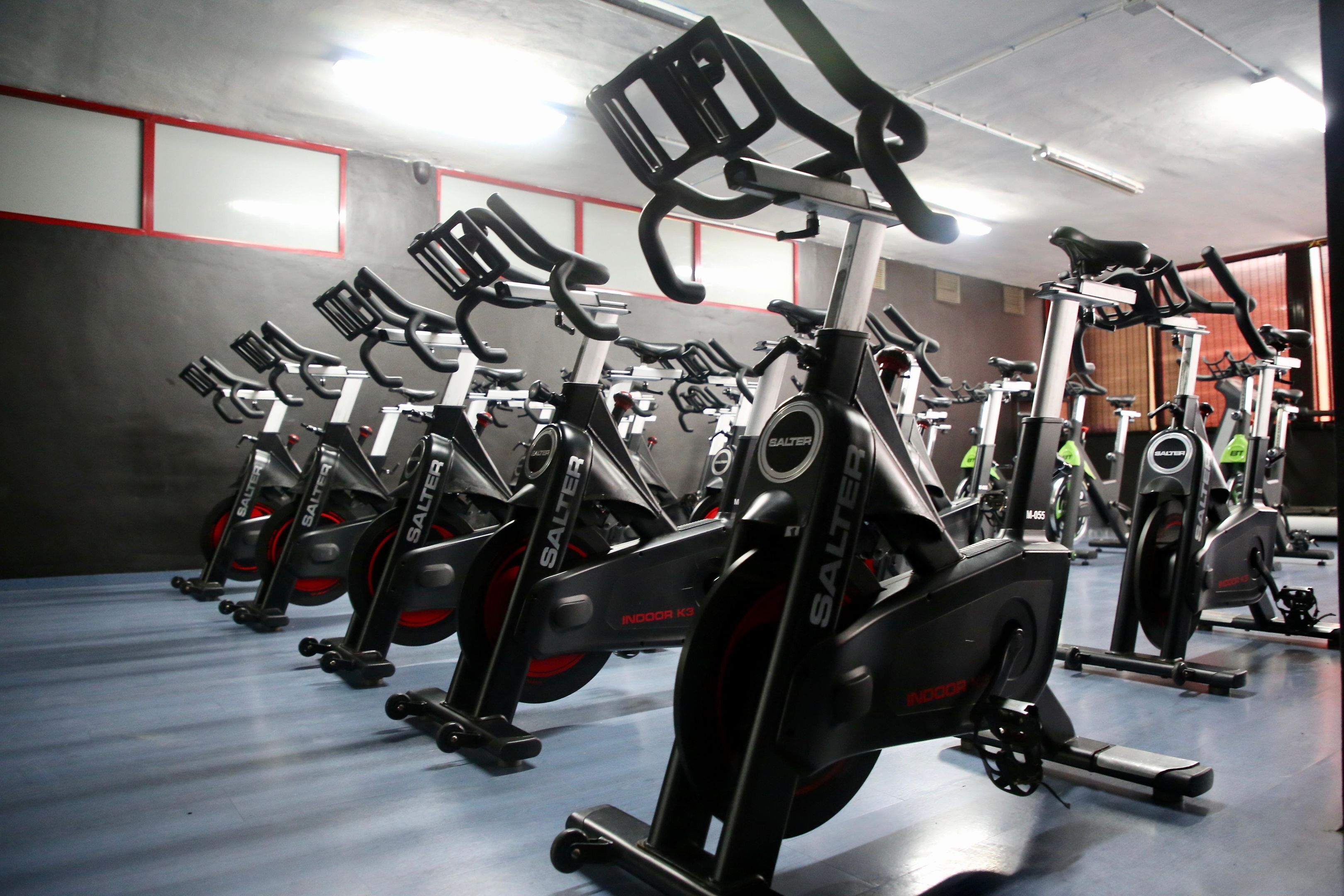 A row of stationary bikes in a gym with a red and grey color scheme.