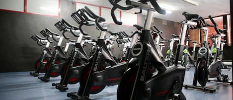 File di biciclette stagne in palestra, con colori rosso e grigio.
