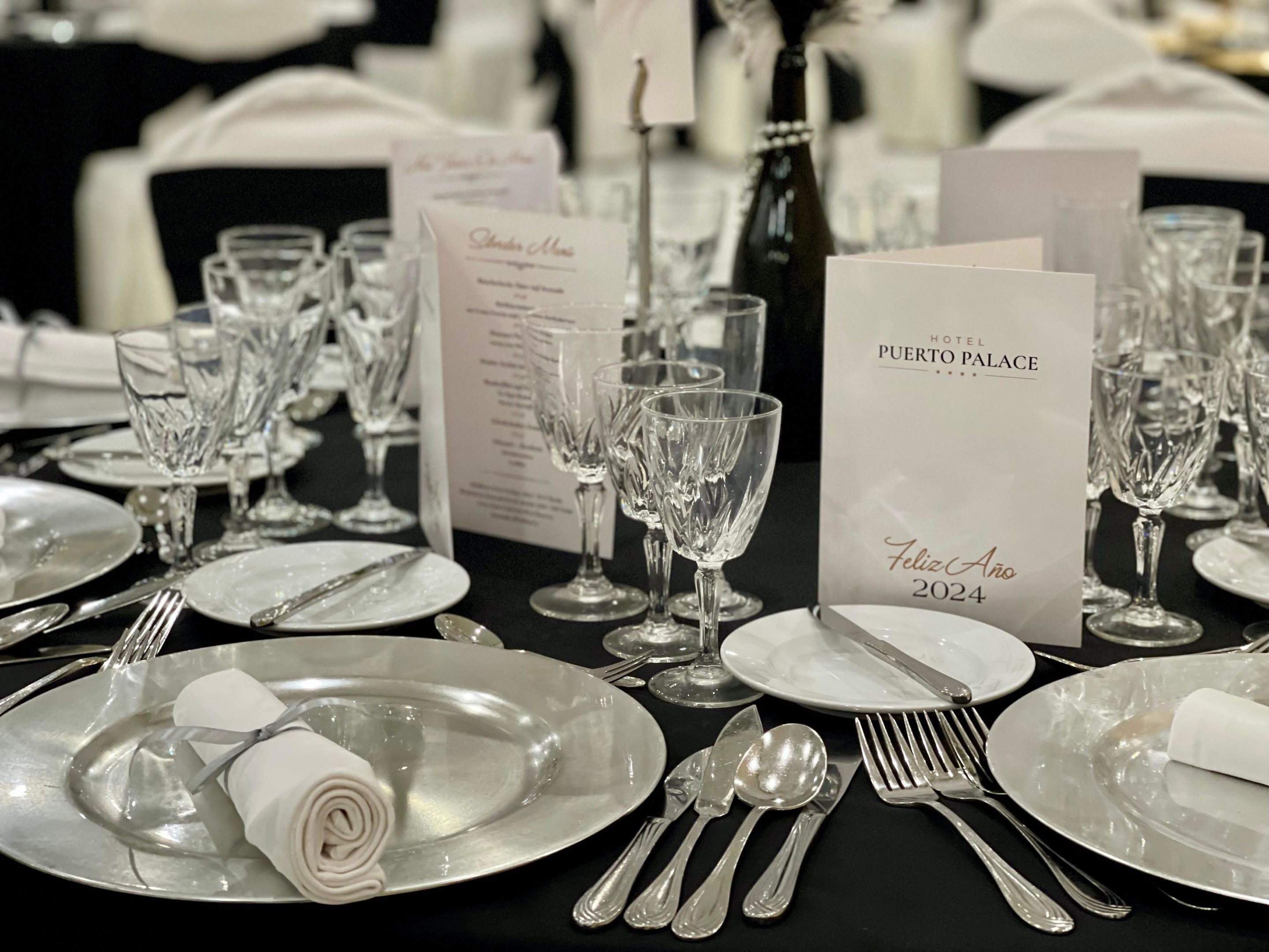 A table set for a formal event with clear glassware, silverware, and a menu card for Puerto Rico Palace.