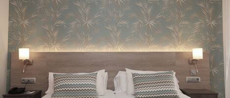 Una habitación de hotel con una cama grande, dos mesitas de noche y una pared con un diseño de hojas.