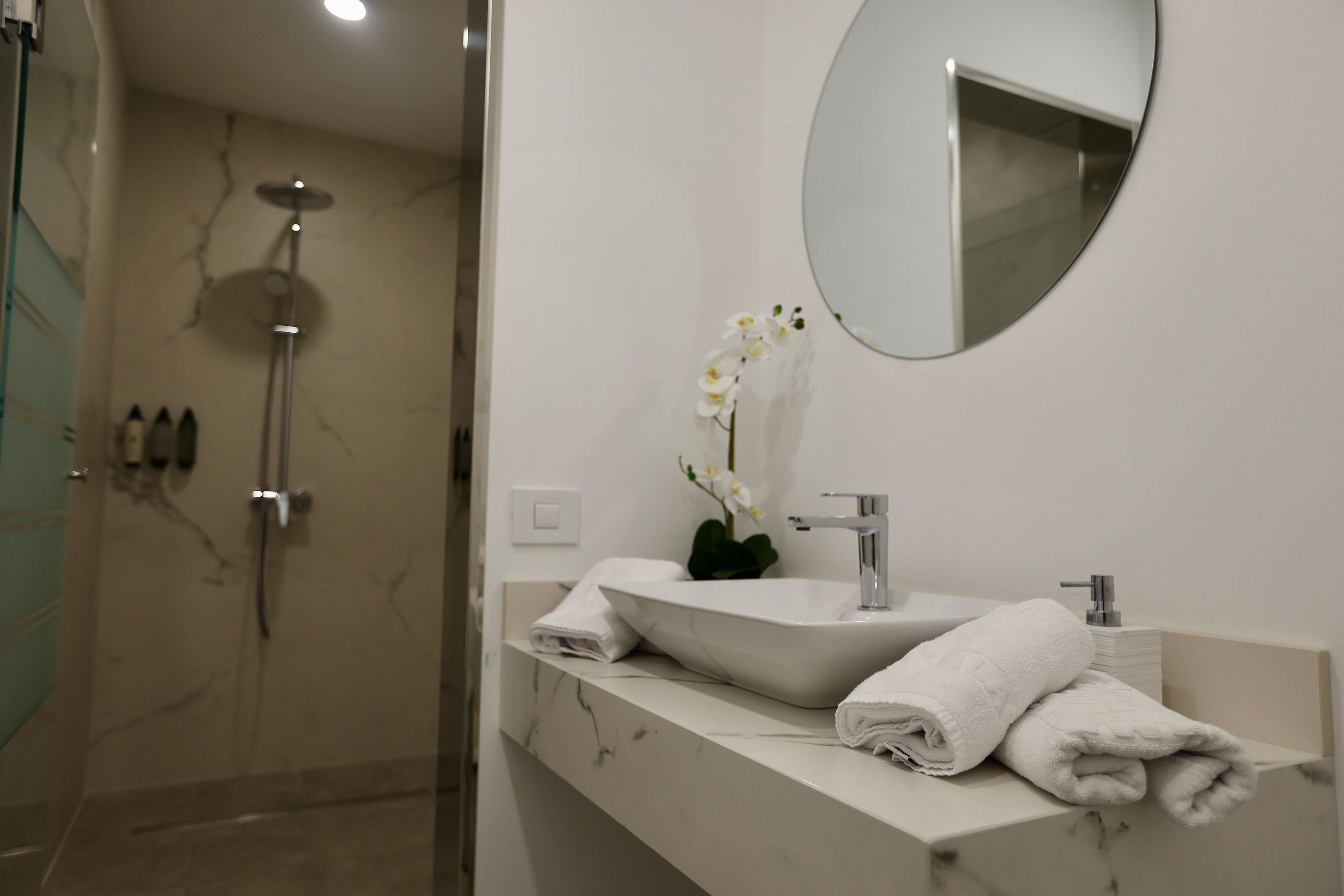 Une salle de bain moderne avec un lavabo blanc, un miroir et une douche.