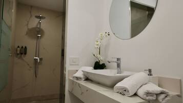 Un baño moderno con un lavabo blanco, espejo y ducha.