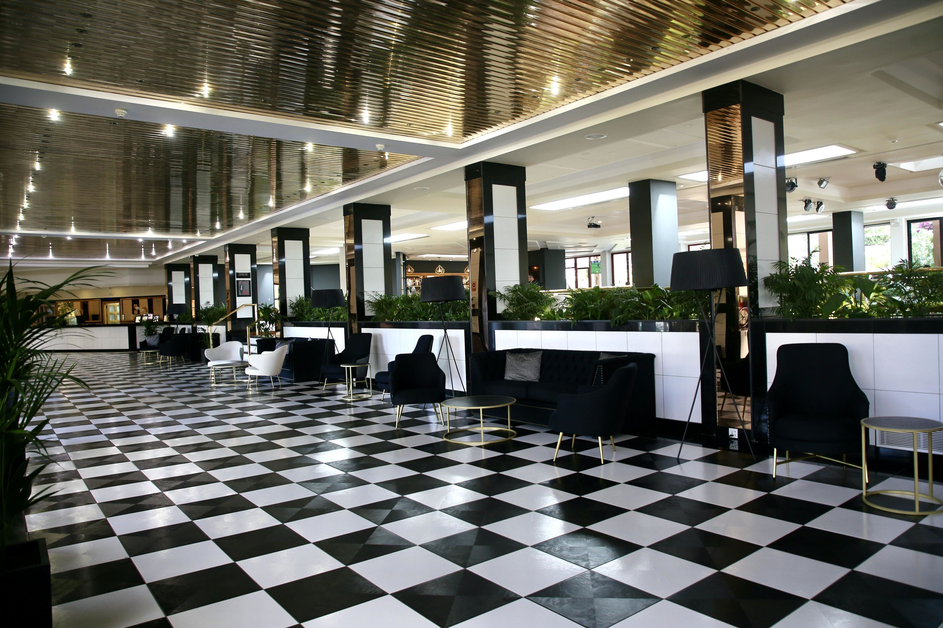 Un vestíbulo con suelo a cuadros, muebles negros y blancos y un mostrador de recepción.