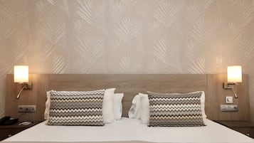 A hotel room with a large bed, two nightstands, a wooden headboard, and wall-mounted lamps.