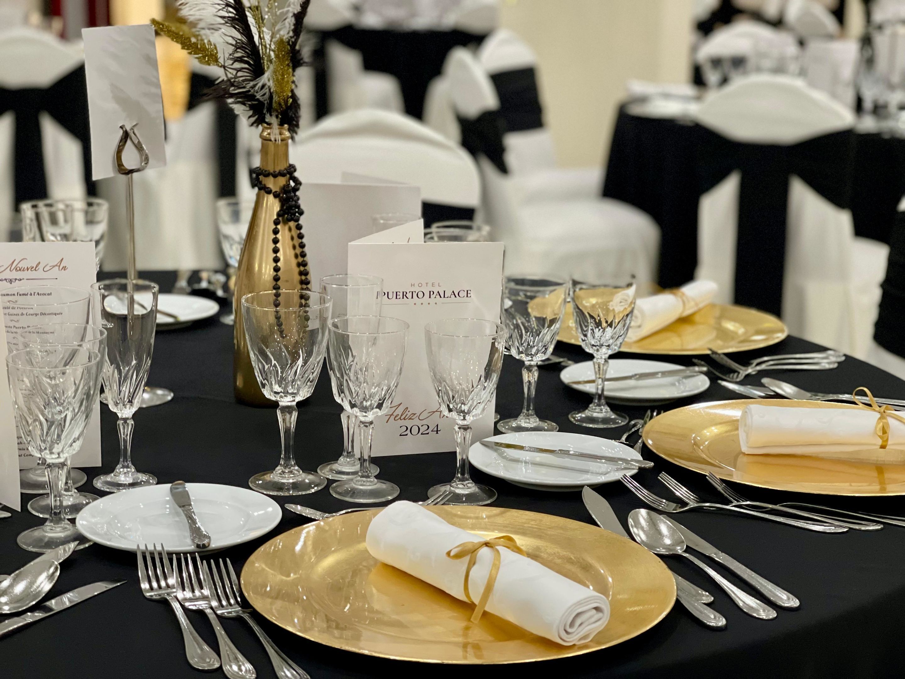 A formal dining table set with clear glassware, gold-rimmed plates, and silver cutlery.
