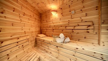 Una sauna de madera con bancos, un perchero para toallas y una lámpara en la pared.
