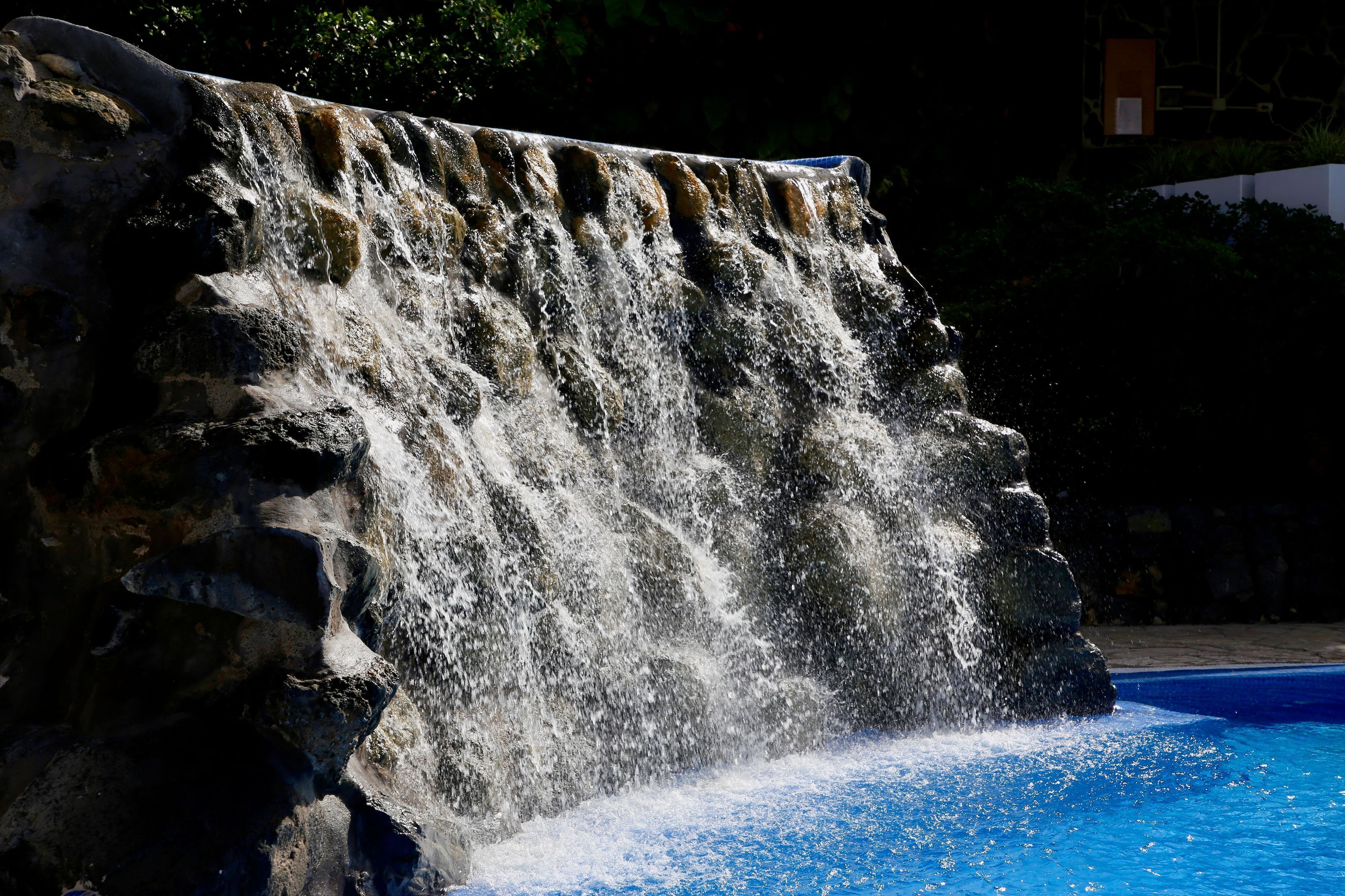 Ein Wasserfall mit herabstürzendem Wasser über einen Felsen in einen Pool.