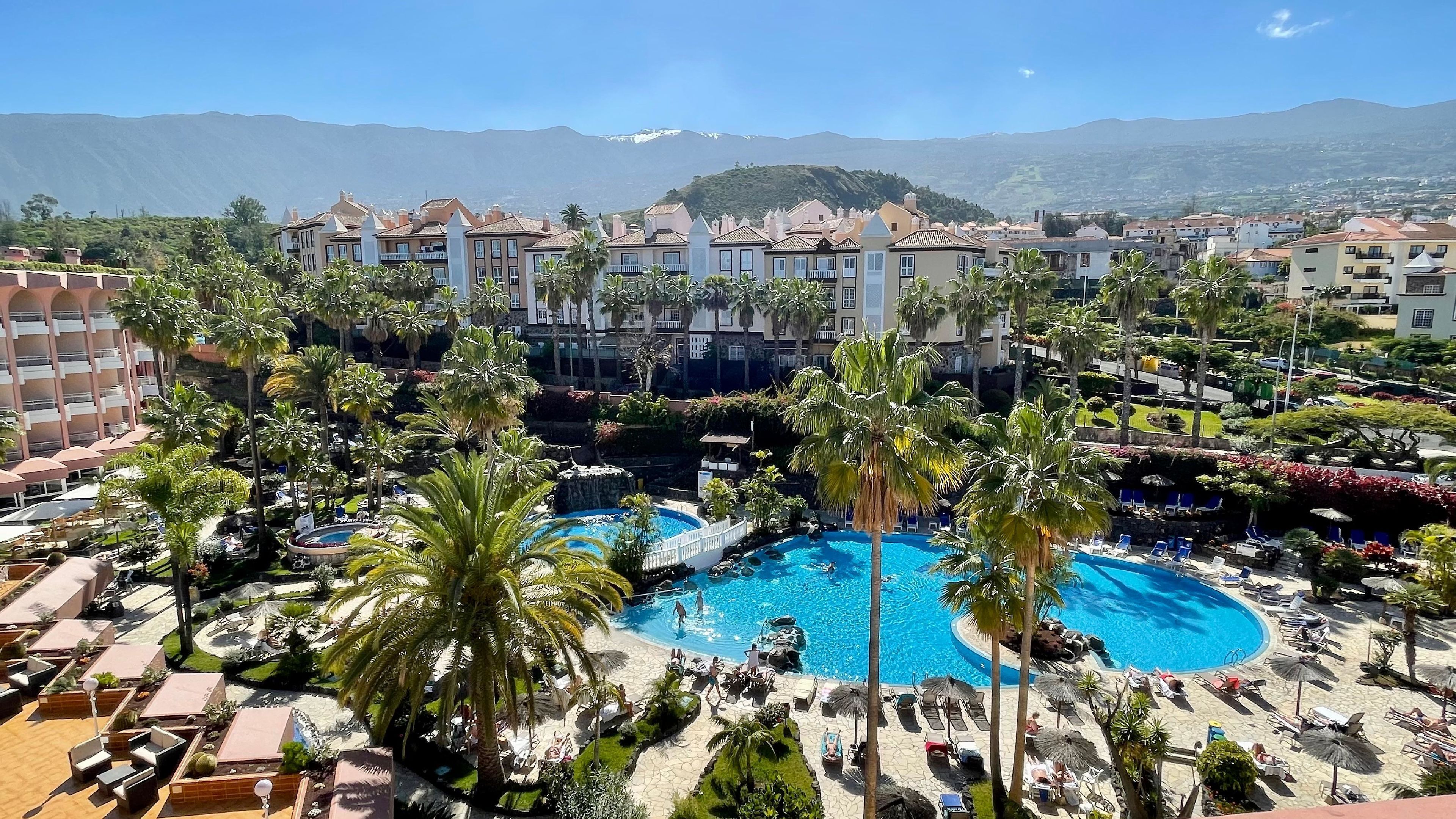 A resort with multiple swimming pools surrounded by palm trees and lounge chairs.