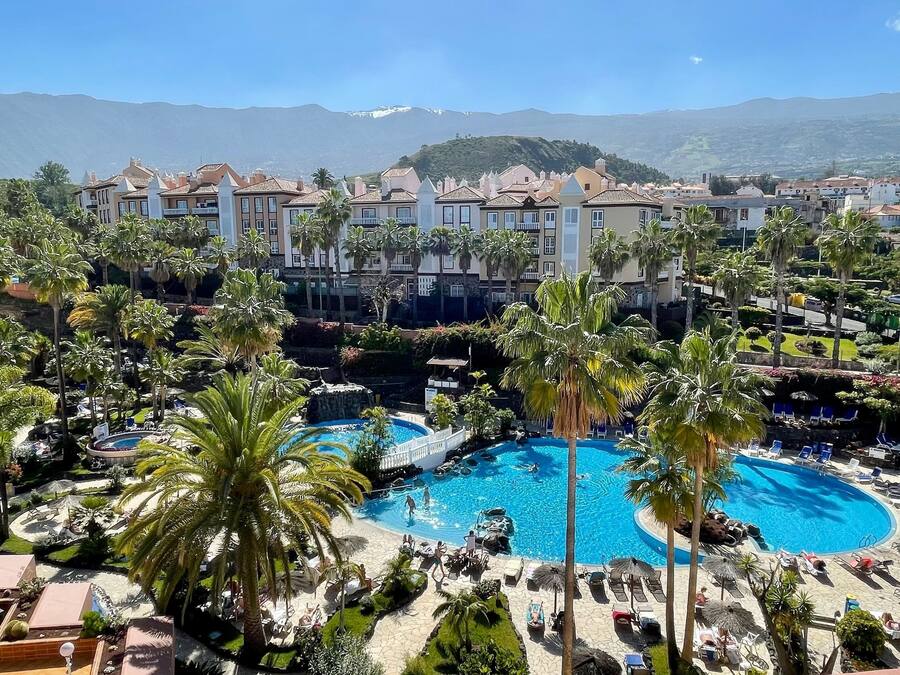 A resort with multiple swimming pools surrounded by palm trees and lounge chairs.