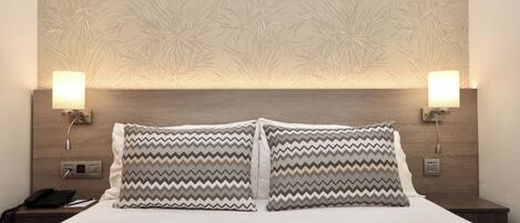 A hotel room with a bed, two nightstands, a phone, and wall-mounted lamps.