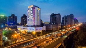 A high-rise hotel with multiple floors, a prominent sign, and a busy highway in the foreground. - Grand Metropark Hotel Hangzhou (Hangzhou)